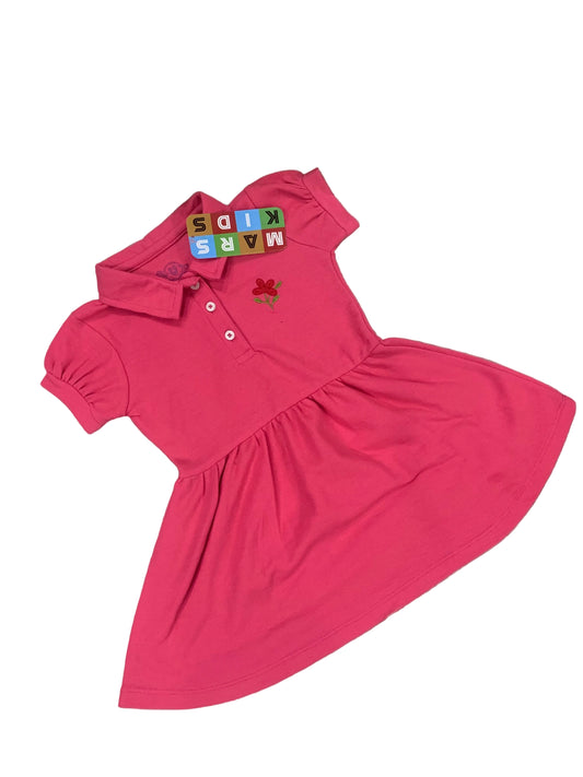 Pink dress with a collar on a fluffy white surface with flowers in the background