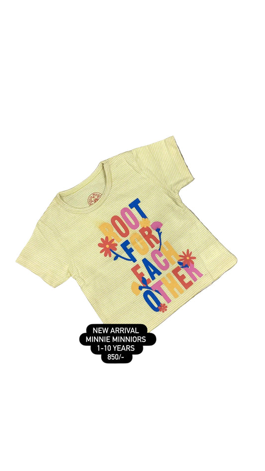 Yellow t-shirt with colorful text on a gray surface with white flowers in the background