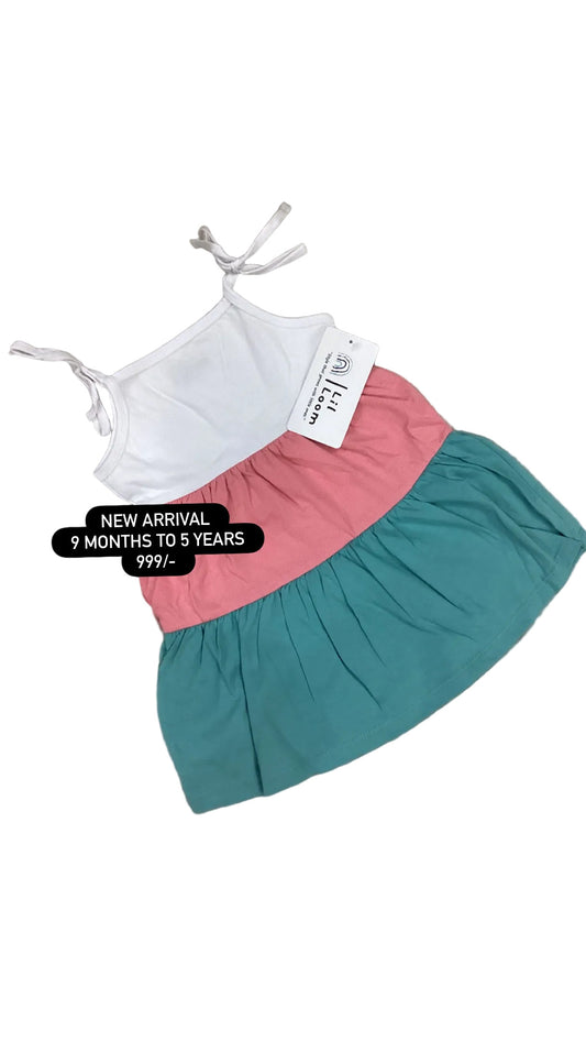 Children's two-tone dress with pink and teal skirt on a textured surface.