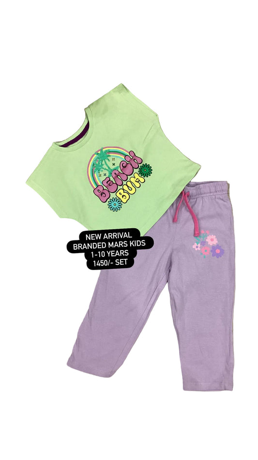 Children's outfit with a green shirt and purple pants on a textured surface with flowers.