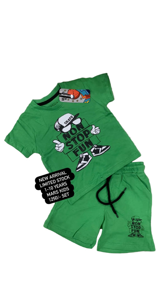 Green children's outfit with graphic design on a textured surface with flowers in the background