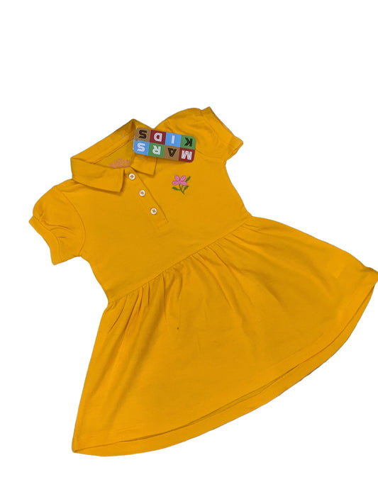 Yellow dress with colorful text and floral design on a textured surface with flowers in the background