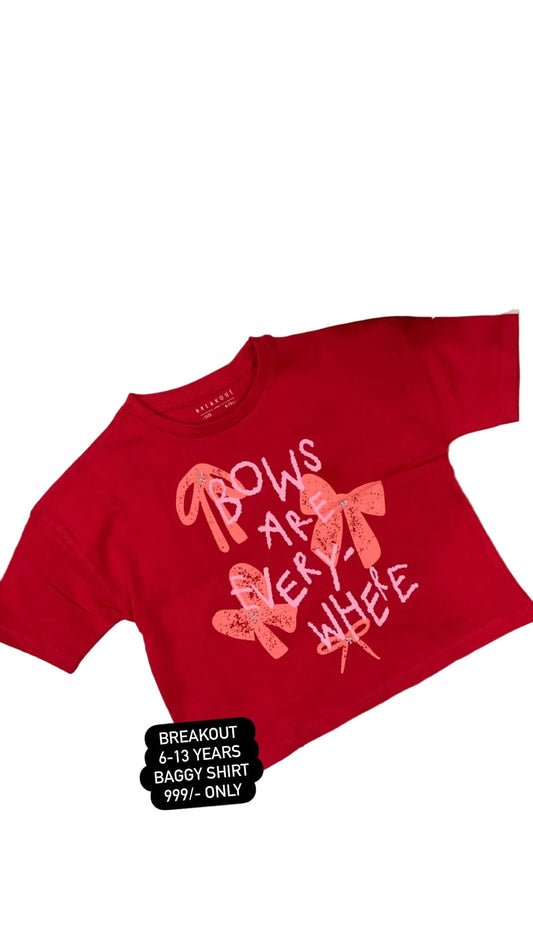 Red shirt with pink text and graphics on a fluffy white surface with flowers.