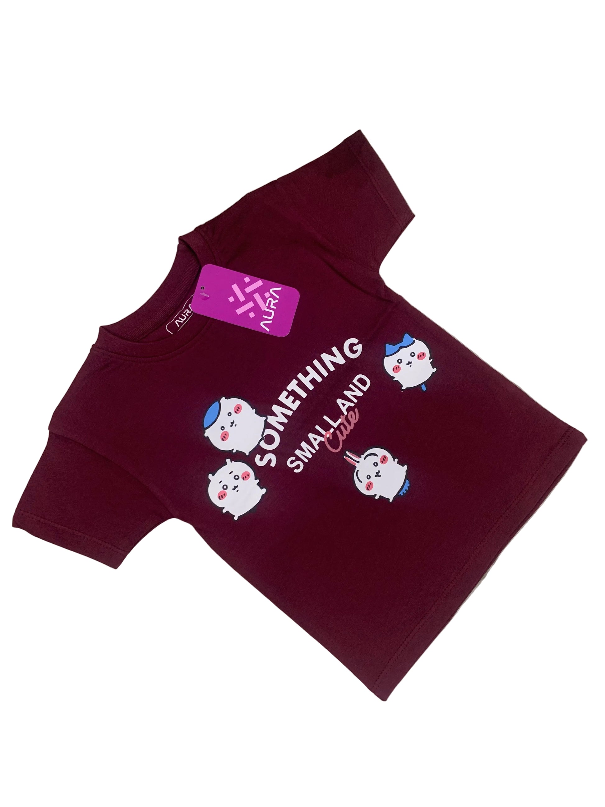 Maroon baby outfit with cartoon characters and text on a fluffy white surface with flowers in the background
