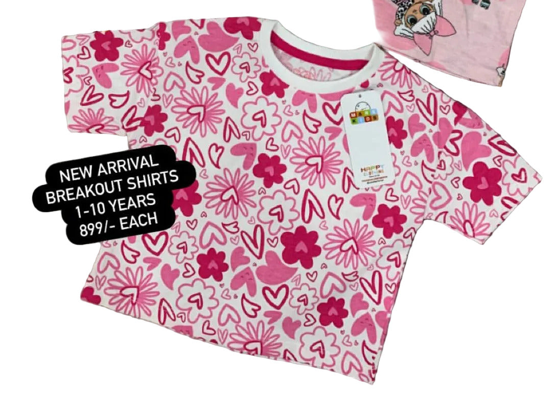 Three children's t-shirts with different patterns on a textured surface with flowers in the background.